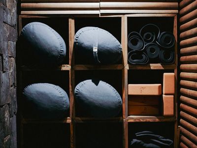 Minimalist yoga equipment arranged neatly on a dark wooden floor.